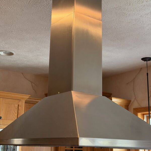 Stainless steel island range hood polished to a shine